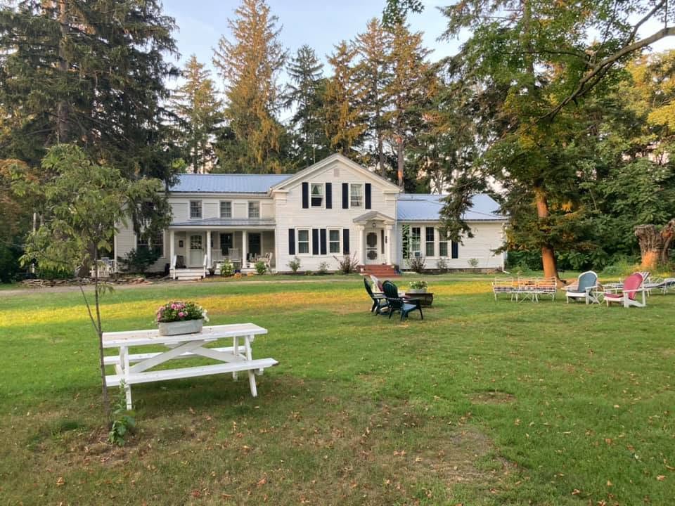 The farmhouse across open lawns at dusk